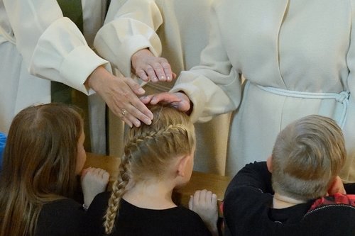 Papit siunaavat alttarille polvistunutta tyttöä. Pappien kädet ovat tytön pään päällä.