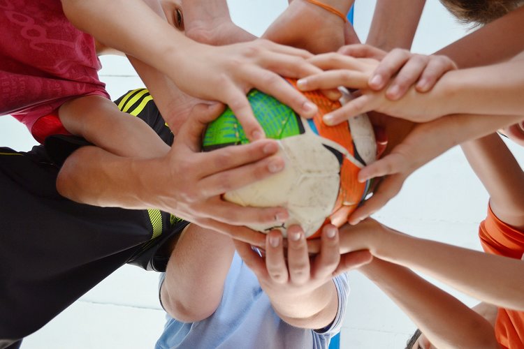 Käsiä pallon ympärillä